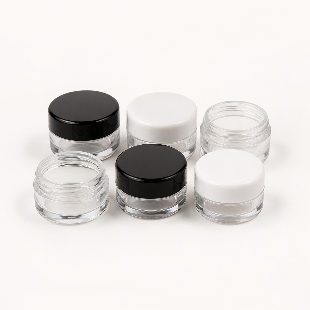 Miniature clear cosmetic sample jars with black and white lids