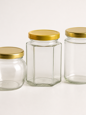 Empty clear round hexagonal and straight-sided honey jars with gold lids
